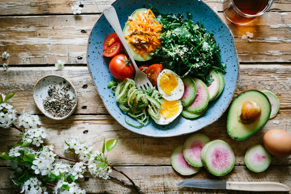 A vibrant, nutrient-packed low-calorie meal featuring fresh vegetables, boiled eggs, and avocado slices on a rustic wooden table, illustrating healthy eating choices.