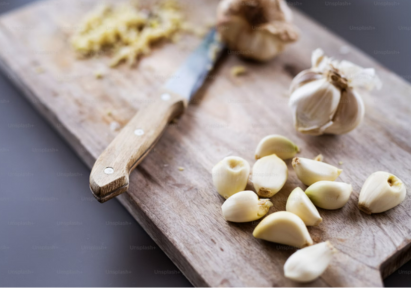 A clove of garlic being peeled on the chopping board.