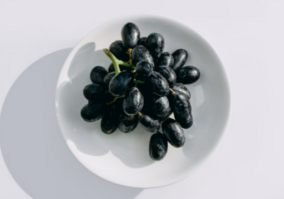 A bowl of fresh black grapes.