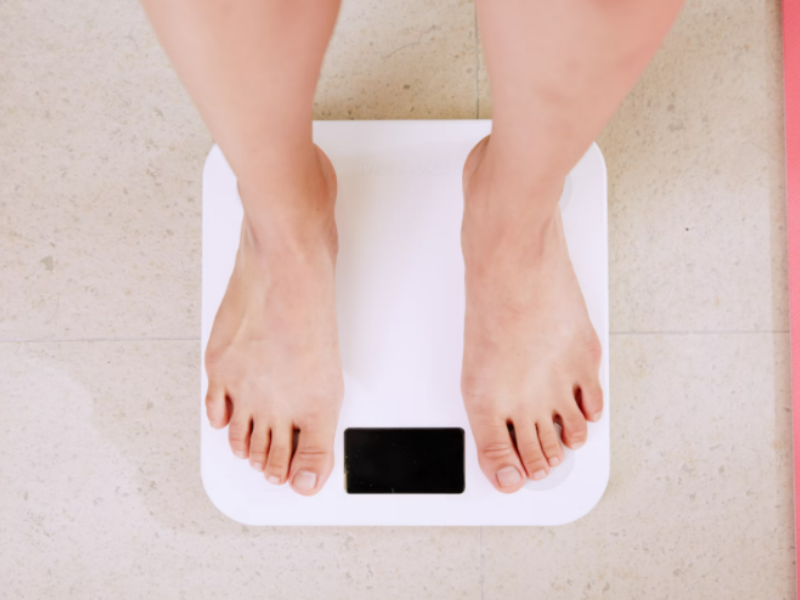 Close-up of feet on a digital scale, representing weight management and tracking progress during a weight loss journey.