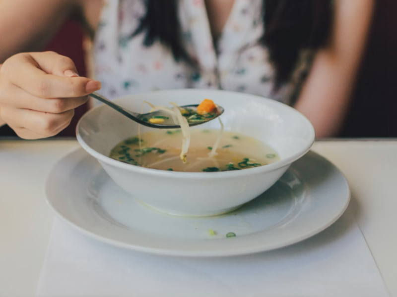 A bowl of chicken soup with light seasoning.