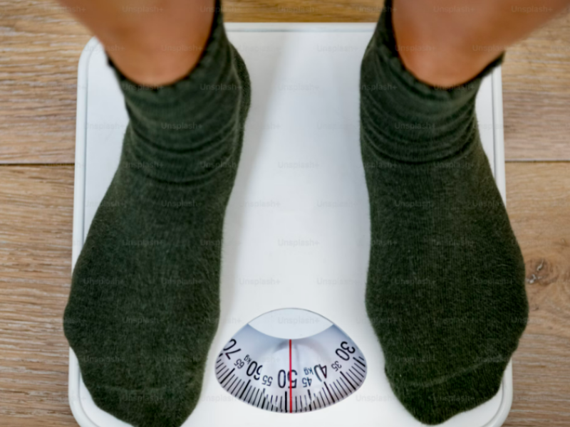 A person focusing on weight loss weighing himself on the scale.